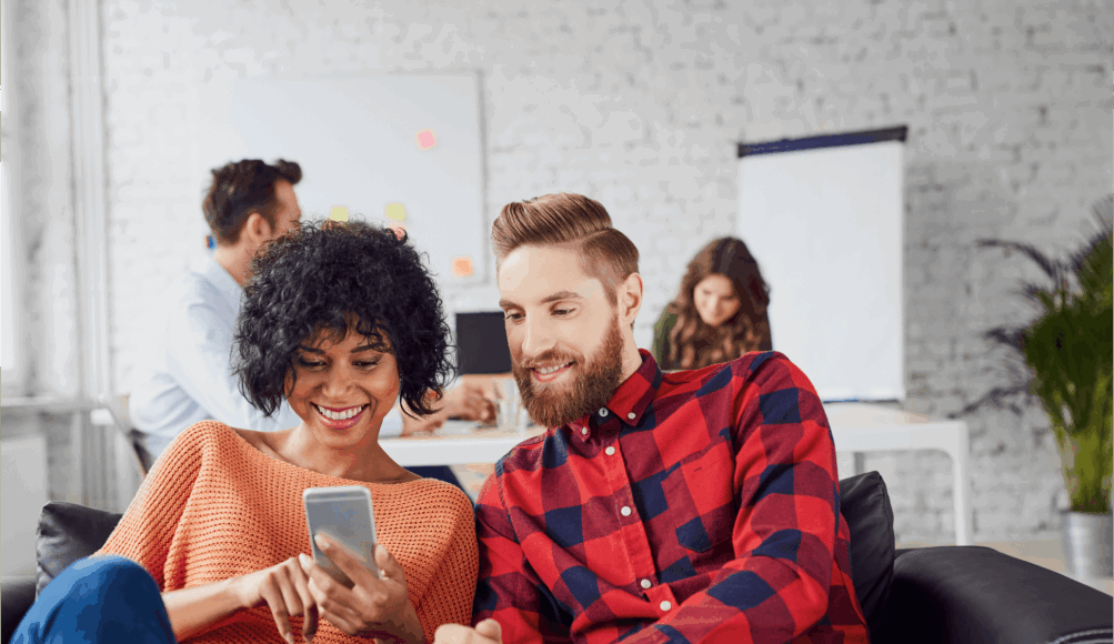 A man and a woman look at a phone screen together|||Elevate Customer Engagement Forum